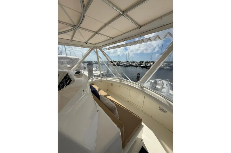 Slide: The Image of 1988 Bertram 43 Flybridge interior with marina view, featuring comfortable seating and clear windows. - 72