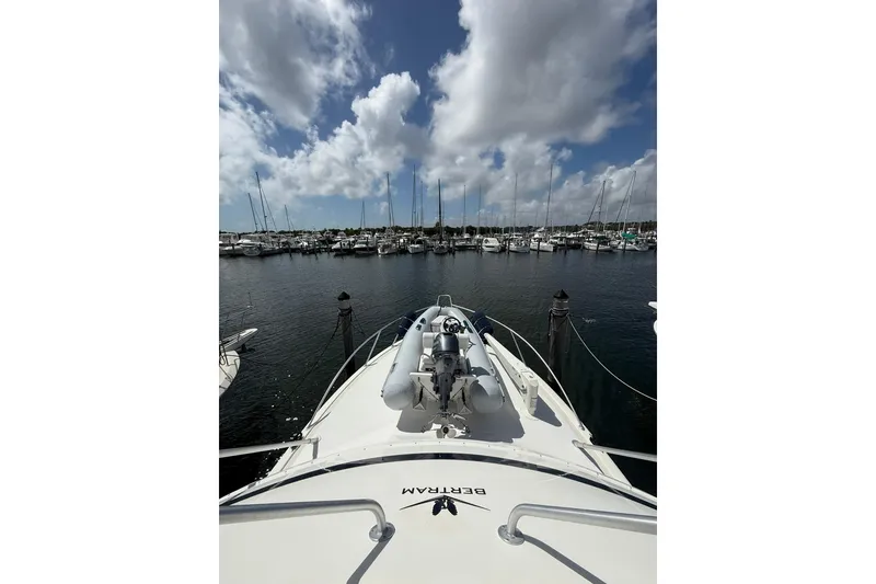 Slide: The Image of 1988 Bertram 43 Flybridge yacht docked in a marina under a cloudy sky. - 77