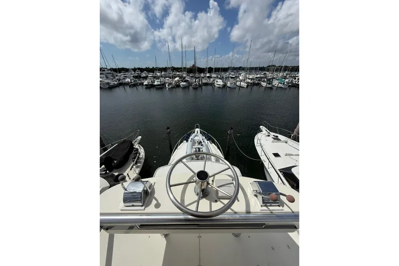 Slide: The Image of 1988 Bertram 43 Flybridge yacht at marina, view from helm, surrounded by boats. - 82