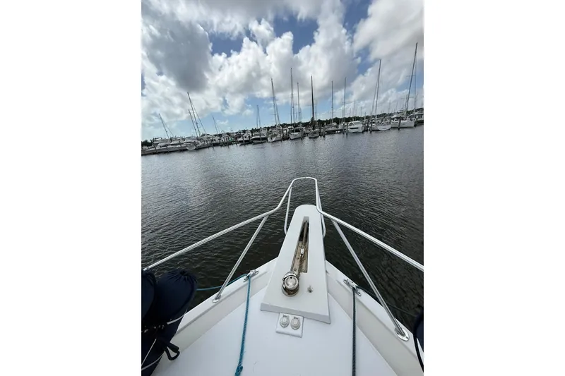 Slide: The Image of Bow view of 1988 Bertram 43 Flybridge in a marina under cloudy skies. - 88