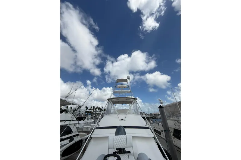 Slide: The Image of 1988 Bertram 43 Flybridge yacht docked under a bright blue sky with clouds. - 91