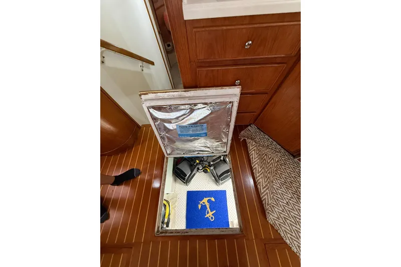 Slide: The Image of 1988 Bertram 43 Flybridge interior with open hatch revealing storage compartment. - 92