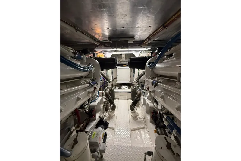 Slide: The Image of Engine room of 1988 Bertram 43 Flybridge, showcasing dual engines and mechanical components. - 95