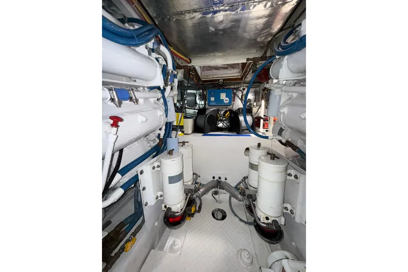 Slide: The Image of Engine room of a 1988 Bertram 43 Flybridge, showcasing mechanical components and piping. - 97