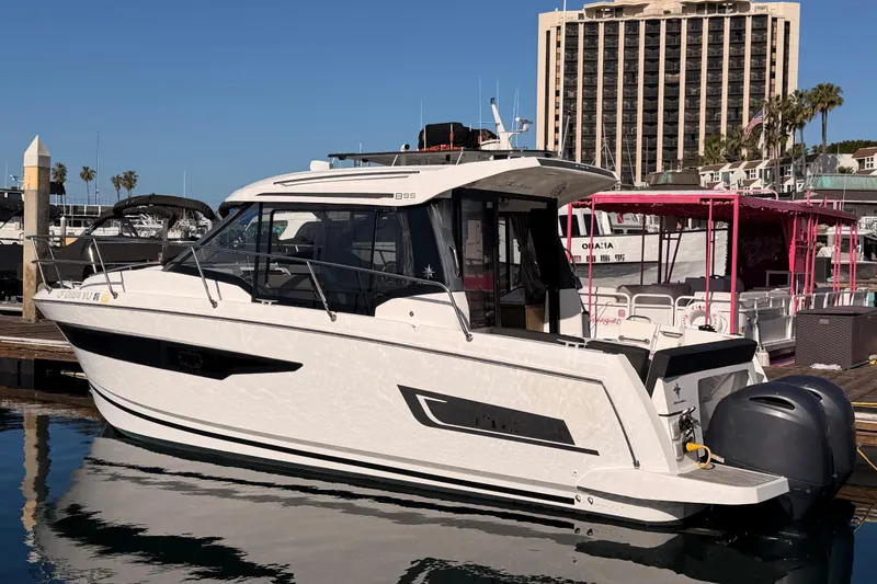 Slide: The Image of 2020 Jeanneau NC 895 boat docked at marina with cityscape background. - 10