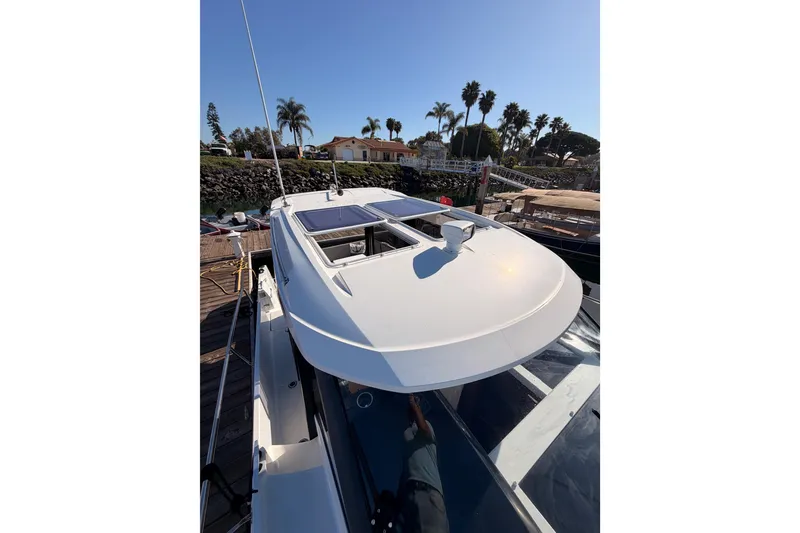 Slide: The Image of 2020 Jeanneau NC 895 boat docked, showcasing sleek design and sunroof under clear blue sky. - 26
