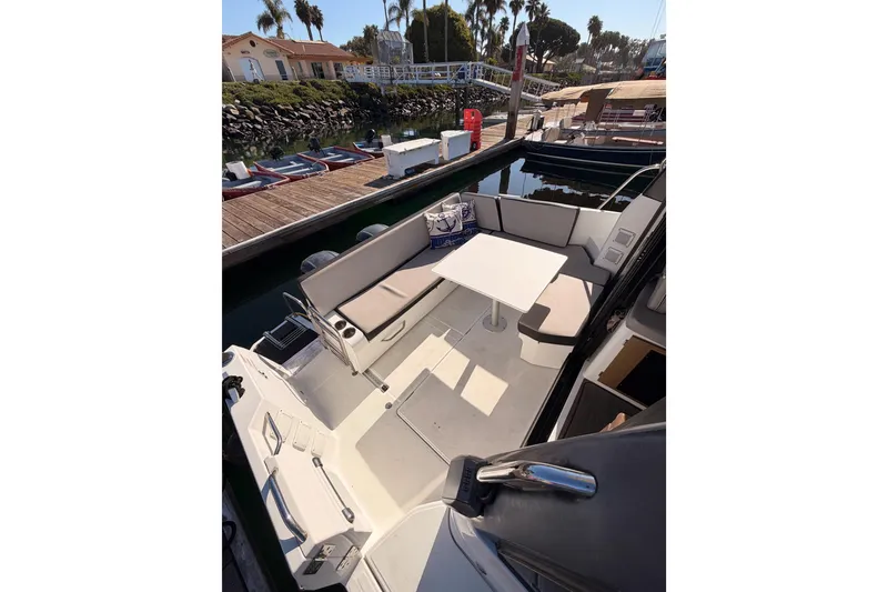 Slide: The Image of 2020 Jeanneau NC 895 boat with spacious seating and table, docked near palm trees. - 29