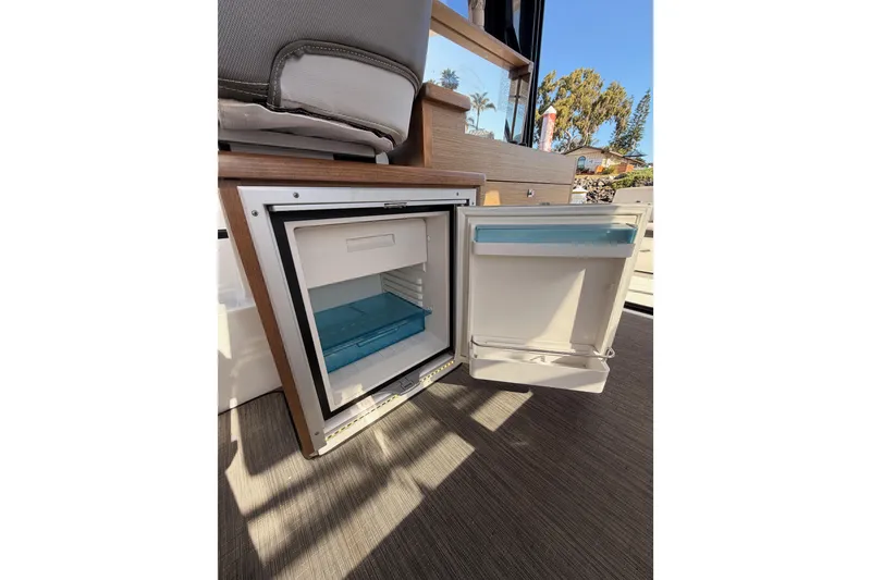 Slide: The Image of Open refrigerator inside 2020 Jeanneau NC 895 boat, showcasing interior storage space. - 44
