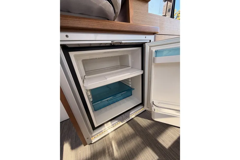 Slide: The Image of Open refrigerator inside 2020 Jeanneau NC 895 boat, showcasing storage compartments. - 45