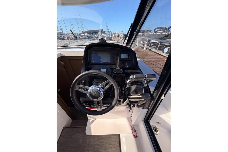 Slide: The Image of 2020 Jeanneau NC 895 helm with steering wheel and navigation controls. - 48