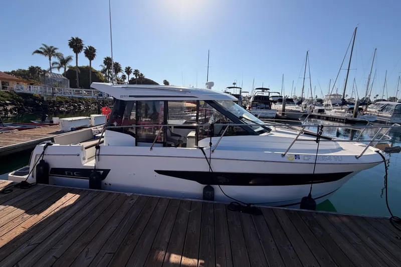 Slide: The Image of 2020 Jeanneau NC 895 boat docked at marina, surrounded by other vessels. - 7