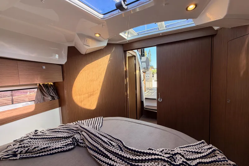 Slide: The Image of 2020 Jeanneau NC 895 cabin interior with skylight, wood paneling, and cozy bedding. - 75