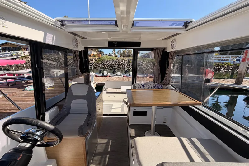 Slide: The Image of 2020 Jeanneau NC 895 boat interior with seating, table, and helm, docked at marina. - 79