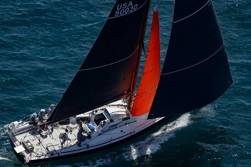 Slide: The Image of Sailing yacht Rogers 46, 2007 model, with black and red sails on open water. - 2