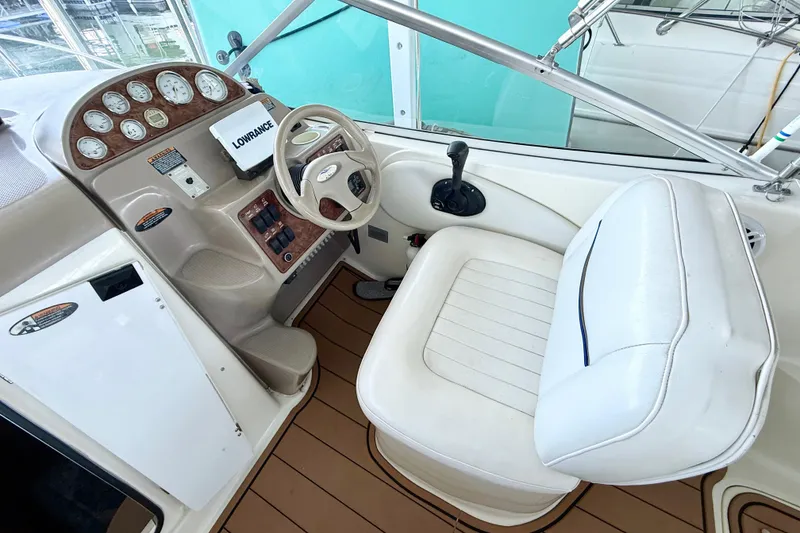 Slide: The Image of 2003 Bayliner 265 boat helm with steering wheel, gauges, and white captain's seat. - 3