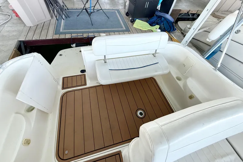 Slide: The Image of 2003 Bayliner 265 boat interior with white seating and wood-patterned flooring. - 34