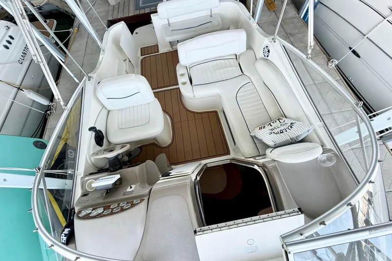 Slide: The Image of 2003 Bayliner 265 boat interior with white seating and wooden flooring. - 4