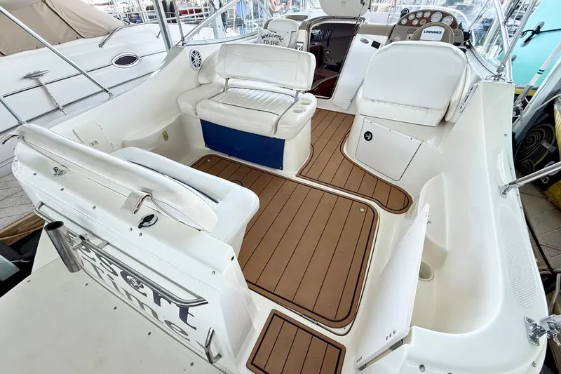 Slide: The Image of 2003 Bayliner 265 boat interior with white seating and wood-style flooring. - 9
