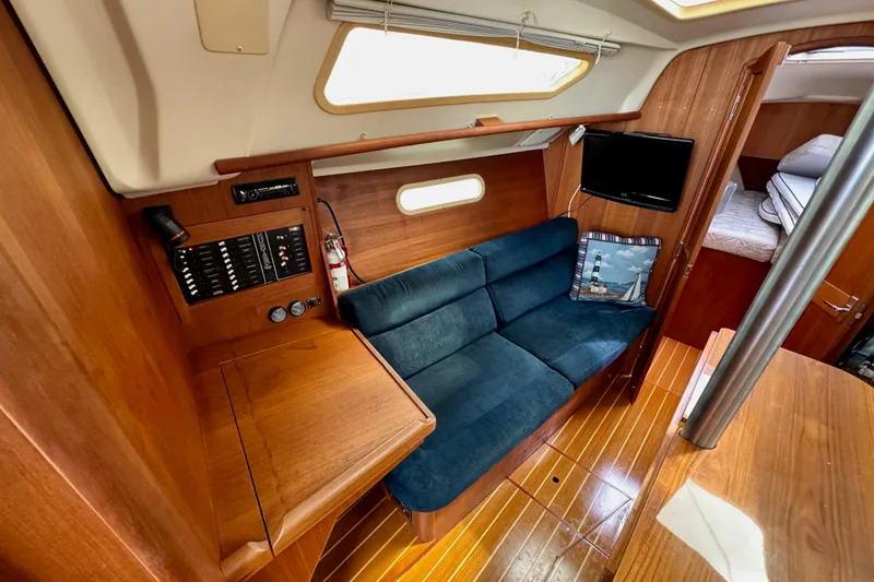 Slide: The Image of Interior of 2001 Hunter 320 sailboat with blue sofa, wooden paneling, and cozy cabin space. - 17