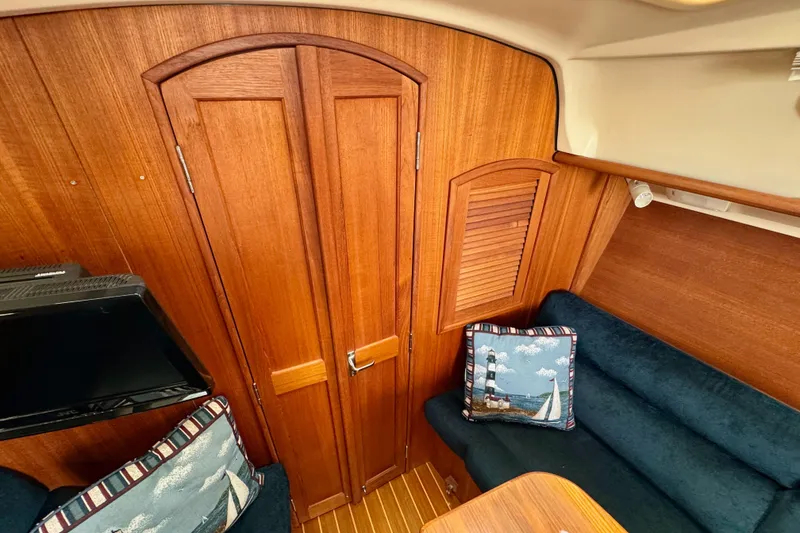 Slide: The Image of Interior of a 2001 Hunter 320 sailboat with wooden paneling and nautical-themed cushions. - 18