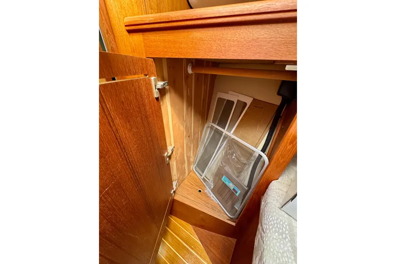 Slide: The Image of Wooden cabinet interior on a 2001 Hunter 320 sailboat, showing storage space and items. - 19