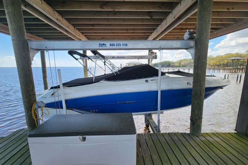 The Image of 2018 Stingray 235 LR boat on lift, docked by a serene waterfront. - 0