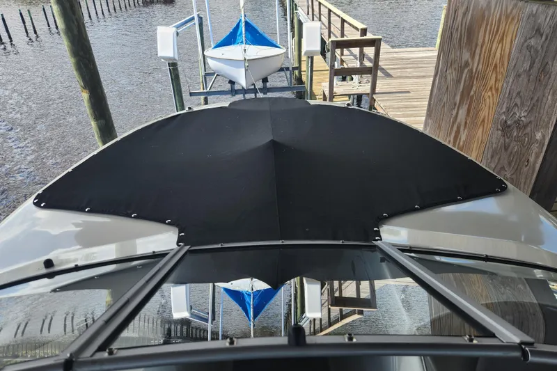Slide: The Image of 2018 Stingray 235 LR boat docked with black cover, wooden pier in background. - 10