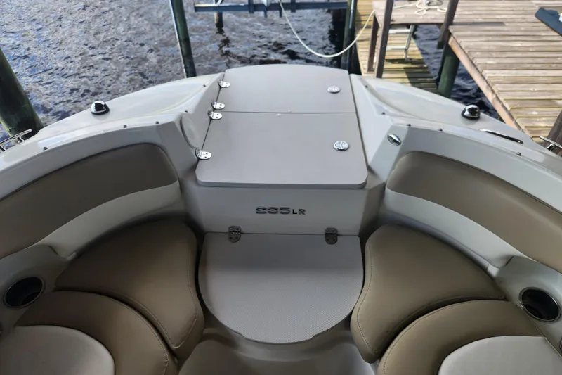 Slide: The Image of 2018 Stingray 235 LR boat interior with beige seating and dock view. - 14
