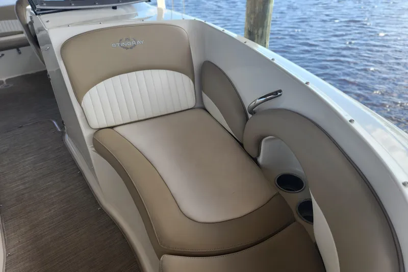Slide: The Image of 2018 Stingray 235 LR boat interior with beige and white seating by the water. - 17