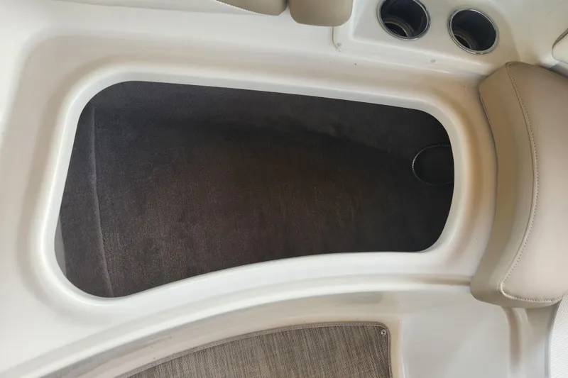 Slide: The Image of 2018 Stingray 235 LR boat interior storage compartment with beige upholstery and cup holders. - 19