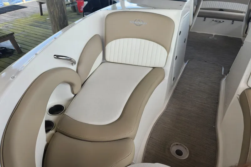 Slide: The Image of 2018 Stingray 235 LR boat interior with beige and white seating, cup holders, and carpeted flooring. - 20
