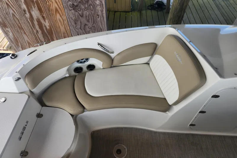 Slide: The Image of 2018 Stingray 235 LR boat interior with beige and white seating, cup holders, and speaker. - 21