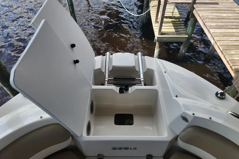 Slide: The Image of 2018 Stingray 235 LR boat with open storage compartment near dock. - 24
