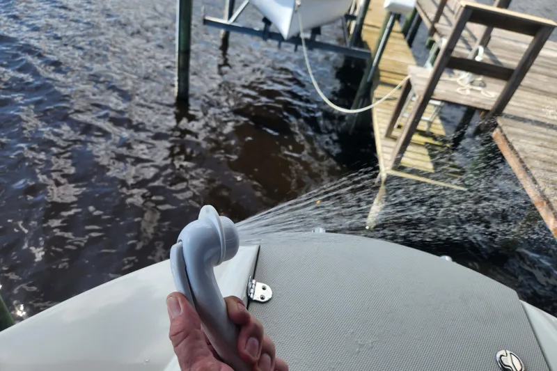 Slide: The Image of Hand holding a spray nozzle on a 2018 Stingray 235 LR boat near a dock. - 26