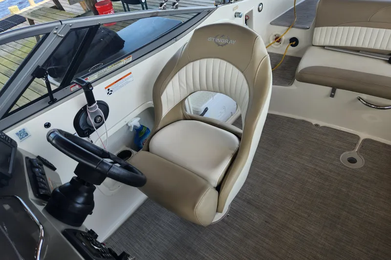 Slide: The Image of 2018 Stingray 235 LR boat interior with steering wheel and seating area. - 32
