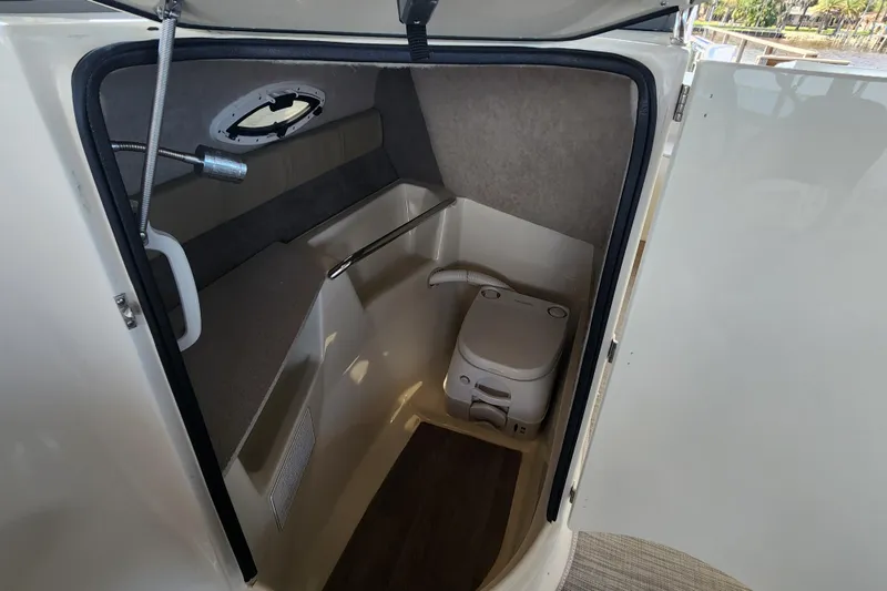 Slide: The Image of 2018 Stingray 235 LR boat interior with compact marine toilet and storage space. - 34