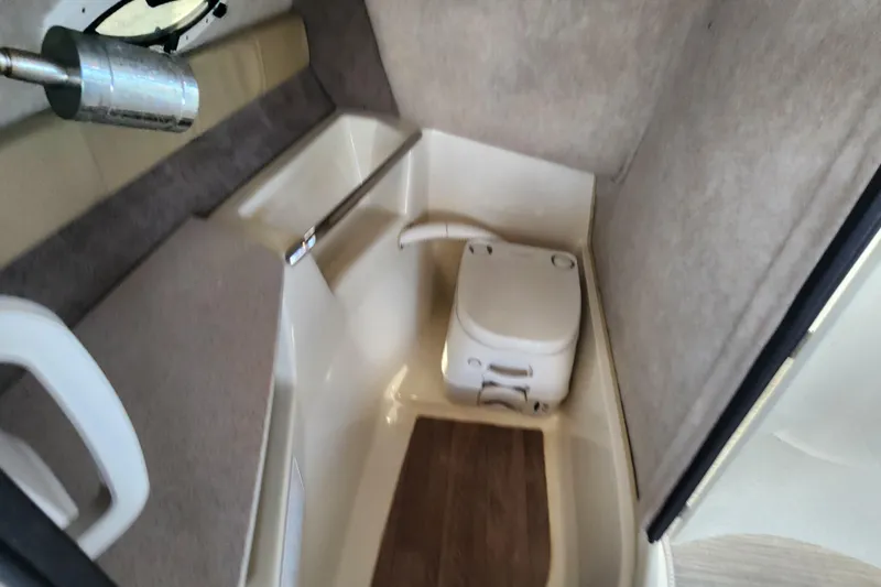 Slide: The Image of 2018 Stingray 235 LR boat interior with compact toilet and seating area. - 35