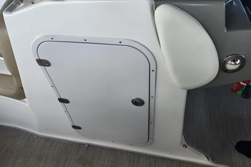 Slide: The Image of 2018 Stingray 235 LR boat interior storage compartment with white door and hinges. - 40