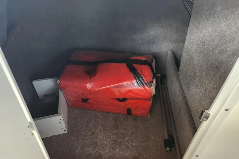 Slide: The Image of Storage compartment in a 2018 Stingray 235 LR boat with red bag and poles. - 41