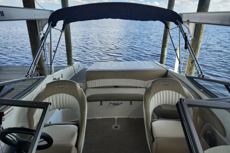 Slide: The Image of 2018 Stingray 235 LR boat interior with seating, steering wheel, and water view. - 42
