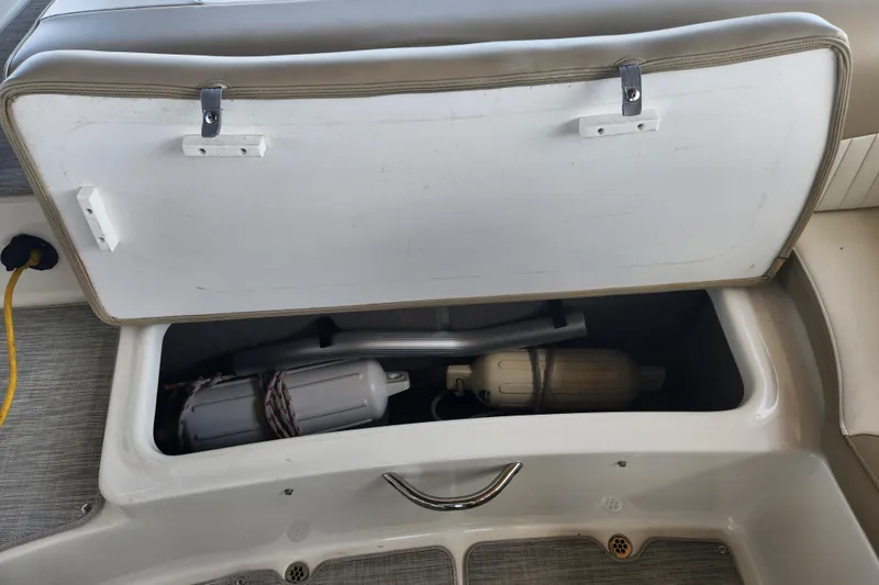 Slide: The Image of Open storage compartment in a 2018 Stingray 235 LR boat, containing fenders and equipment. - 44