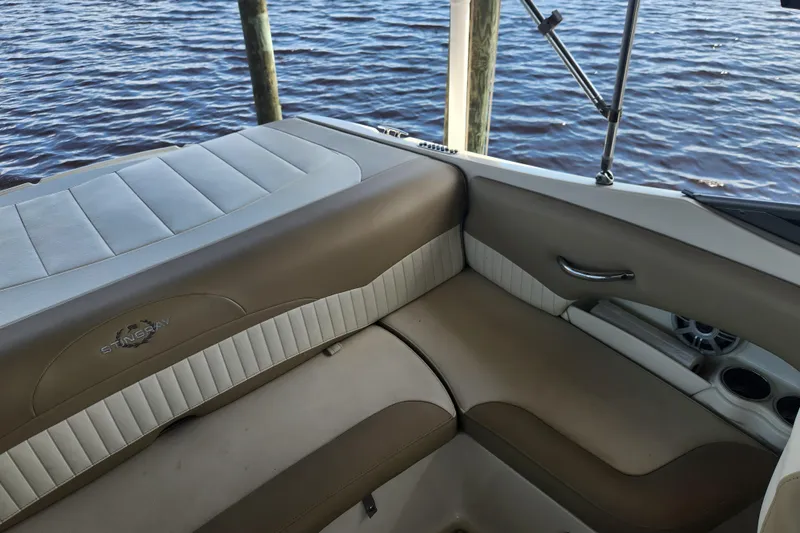 Slide: The Image of 2018 Stingray 235 LR boat interior with beige seating by the water. - 46