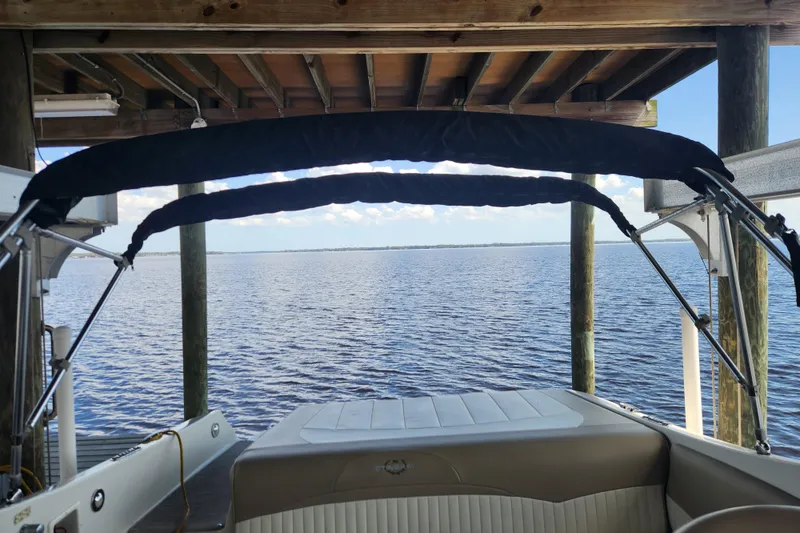 Slide: The Image of 2018 Stingray 235 LR boat docked under wooden shelter, overlooking calm water. - 51