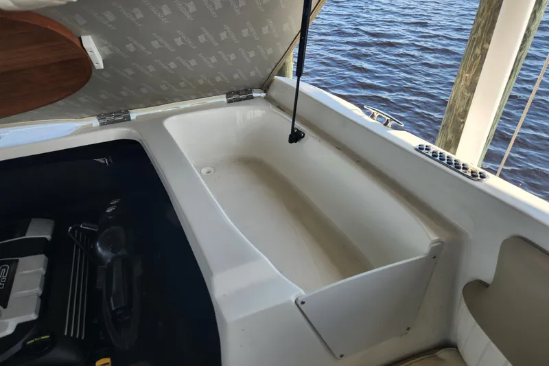 Slide: The Image of 2018 Stingray 235 LR boat engine compartment with open hatch, docked by water. - 54