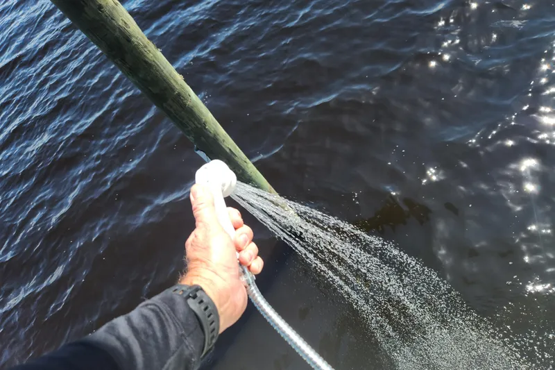 Slide: The Image of Hand spraying water from a Stingray 235 LR boat, 2018 model, near a wooden post. - 57