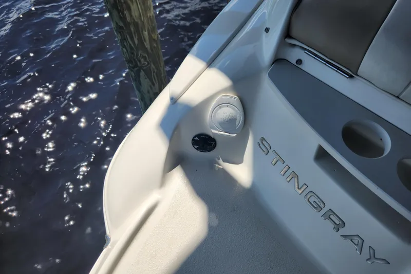 Slide: The Image of 2018 Stingray 235 LR boat interior with logo, near water. - 58
