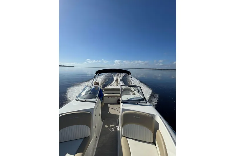 Slide: The Image of 2018 Stingray 235 LR boat cruising on calm water under clear blue sky. - 84