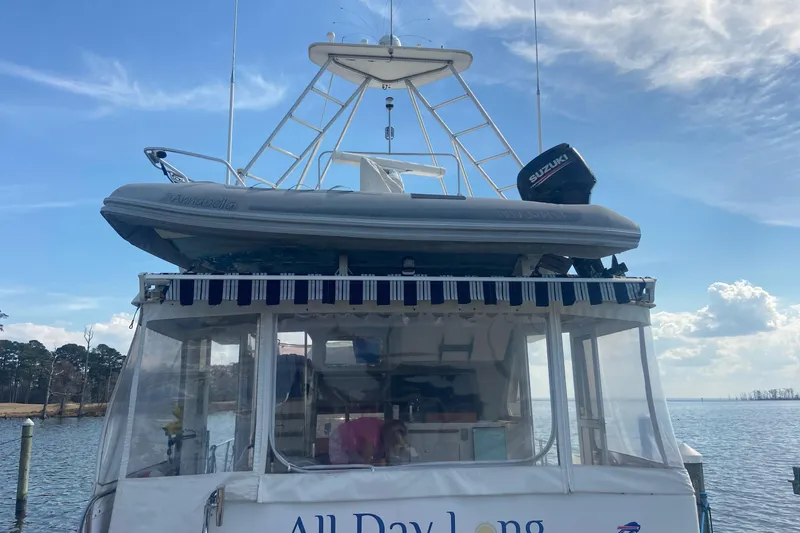Slide: The Image of 1996 President 58 yacht with dinghy and Suzuki motor, docked under a blue sky. - 12