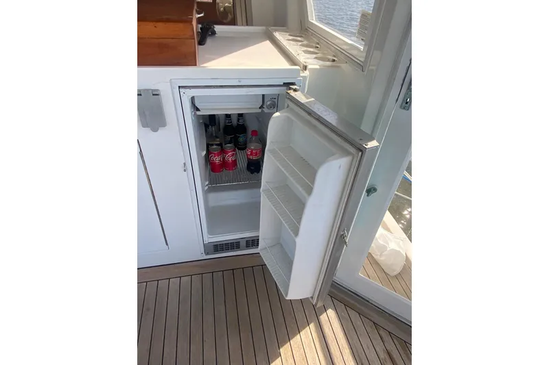 Slide: The Image of Open mini fridge on a boat with Coca-Cola bottles inside, wooden deck visible. - 23