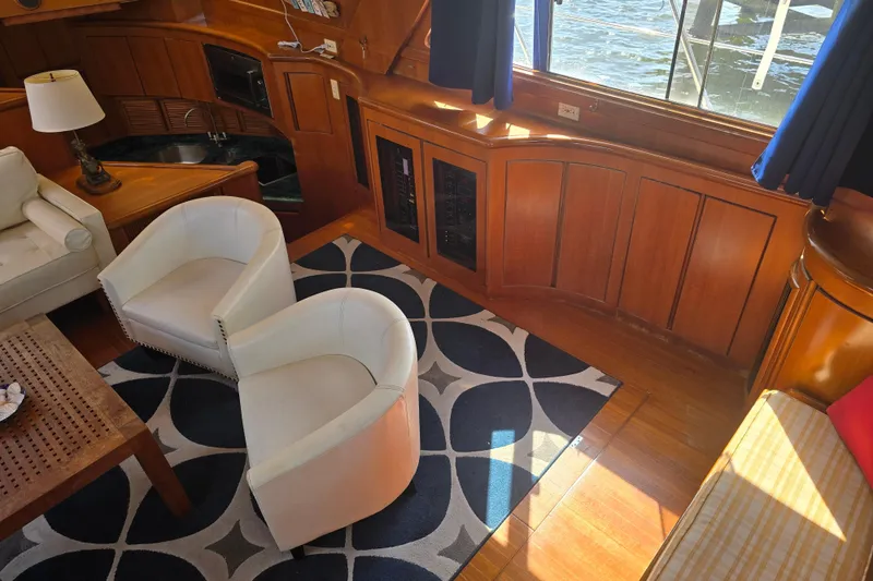 Slide: The Image of Luxurious yacht interior with white chairs, wooden paneling, and a patterned rug, President 58, 1996. - 28